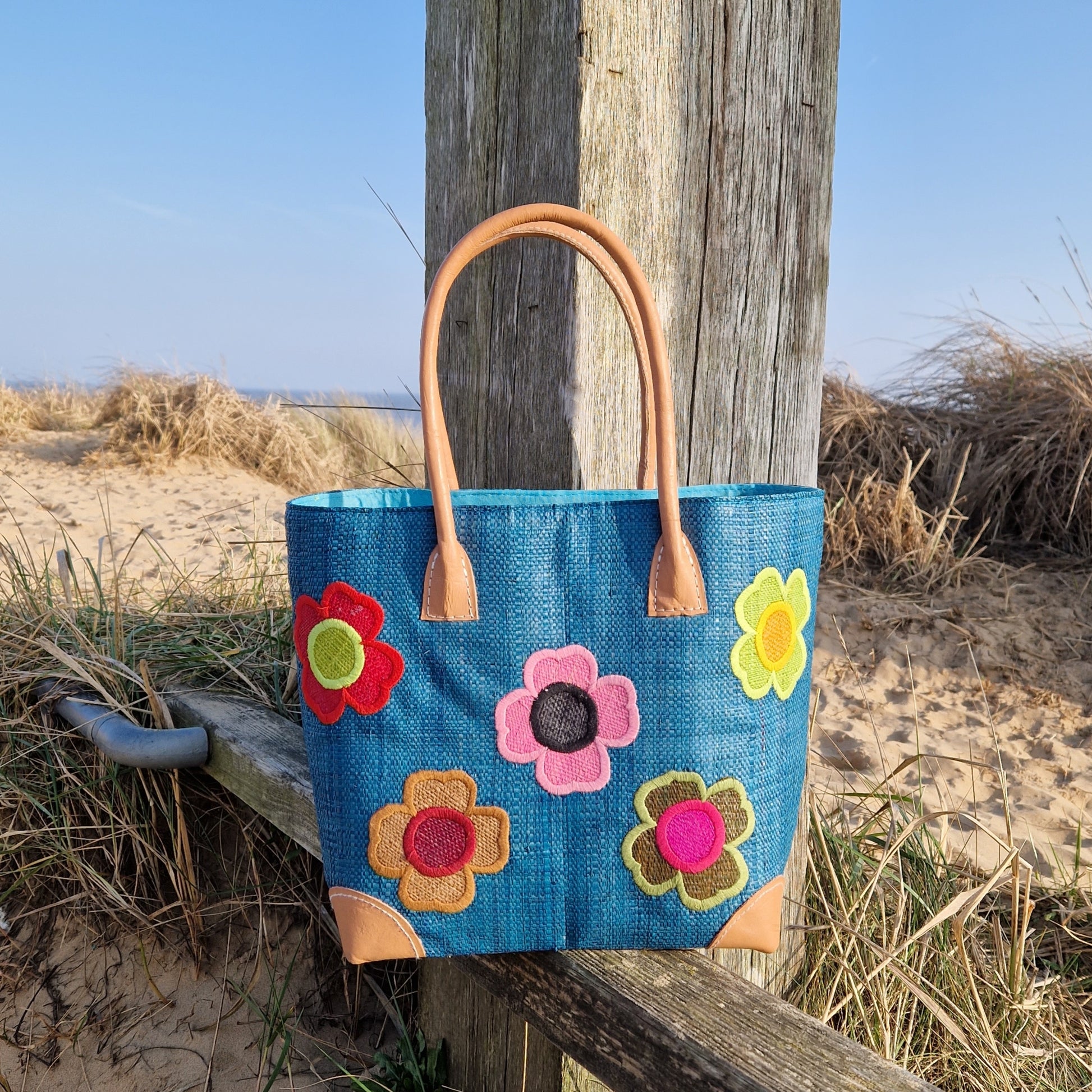 Teal Blue Raffia Basket decorated with coloured flowers.