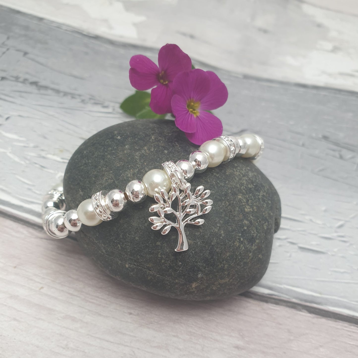 A silver and pearl Stretch bracelet with diamante covered spacers. Hanging from the bracelet is a silver covered Tree of Life charm.