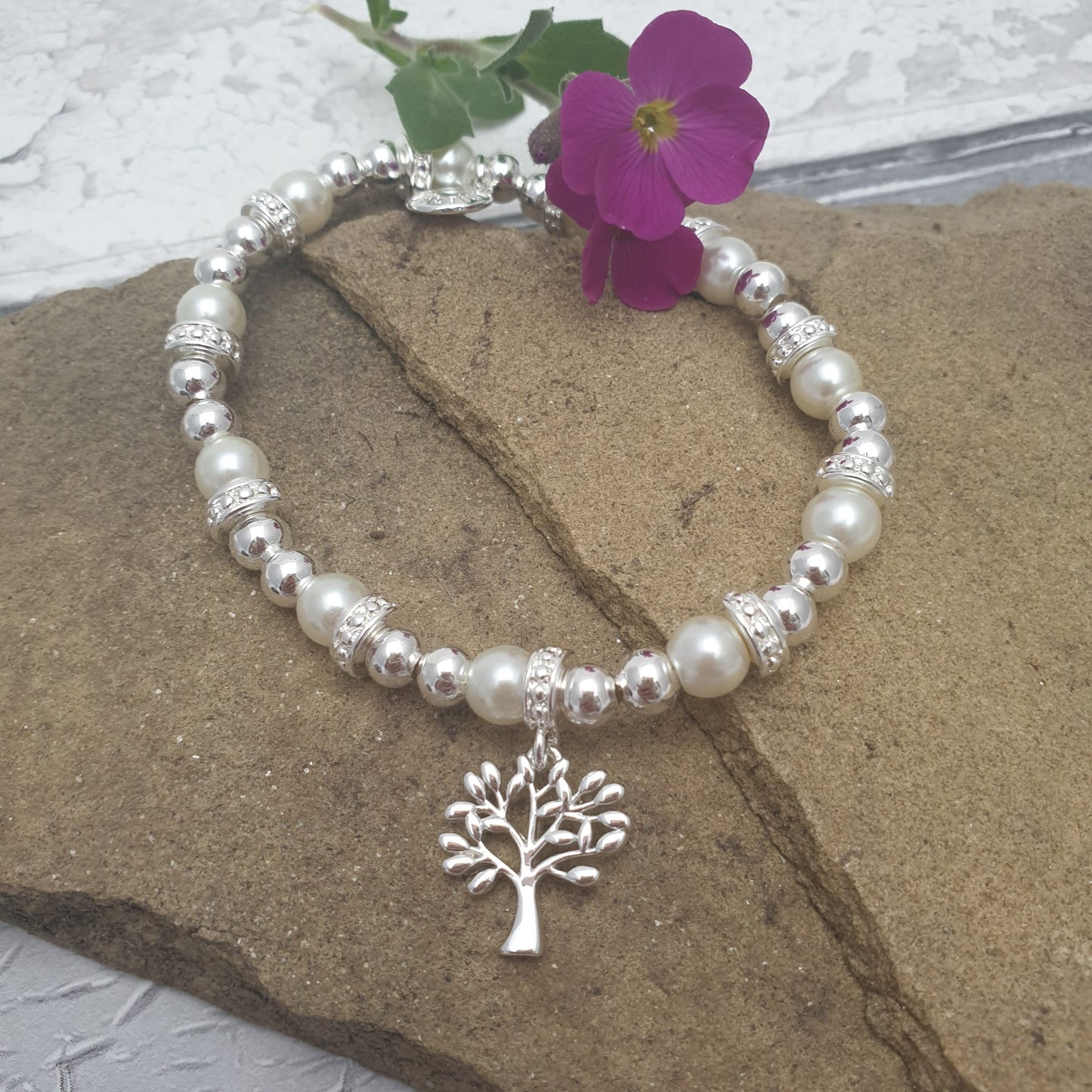 A silver and pearl Stretch bracelet with diamante covered spacers. Hanging from the bracelet is a silver covered Tree of Life charm.
