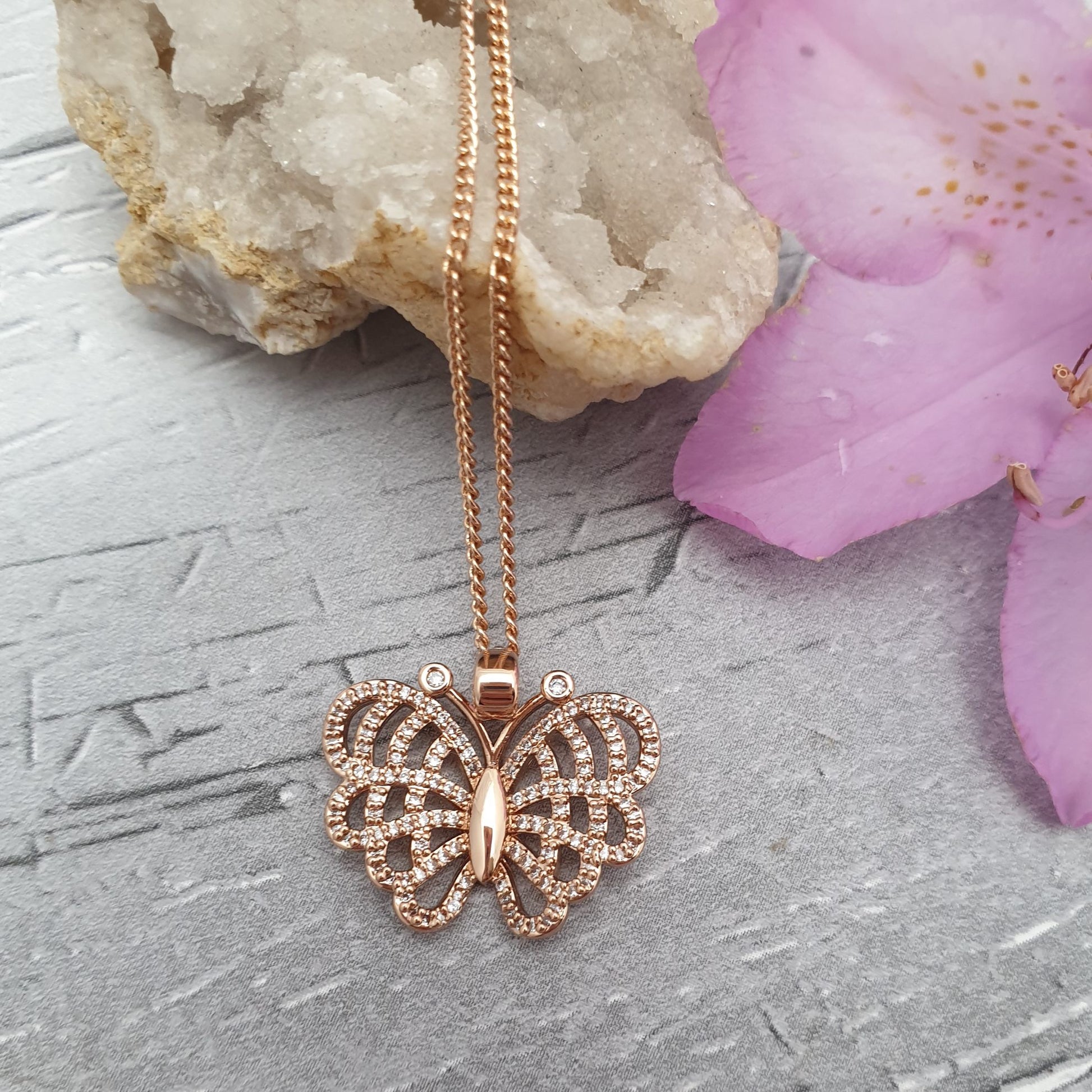 A rose gold coloured chain and pendant necklace. The pendant is an exotic looking butterfly with open wings decorated in diamante crystals