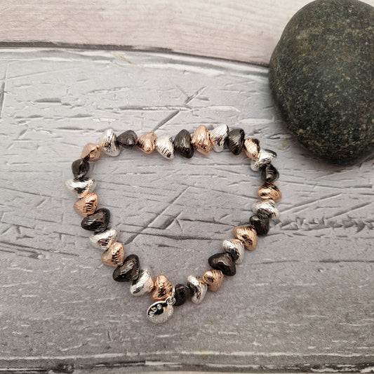 Stretch baraclet made of love hearts in silver, rose gold and black.