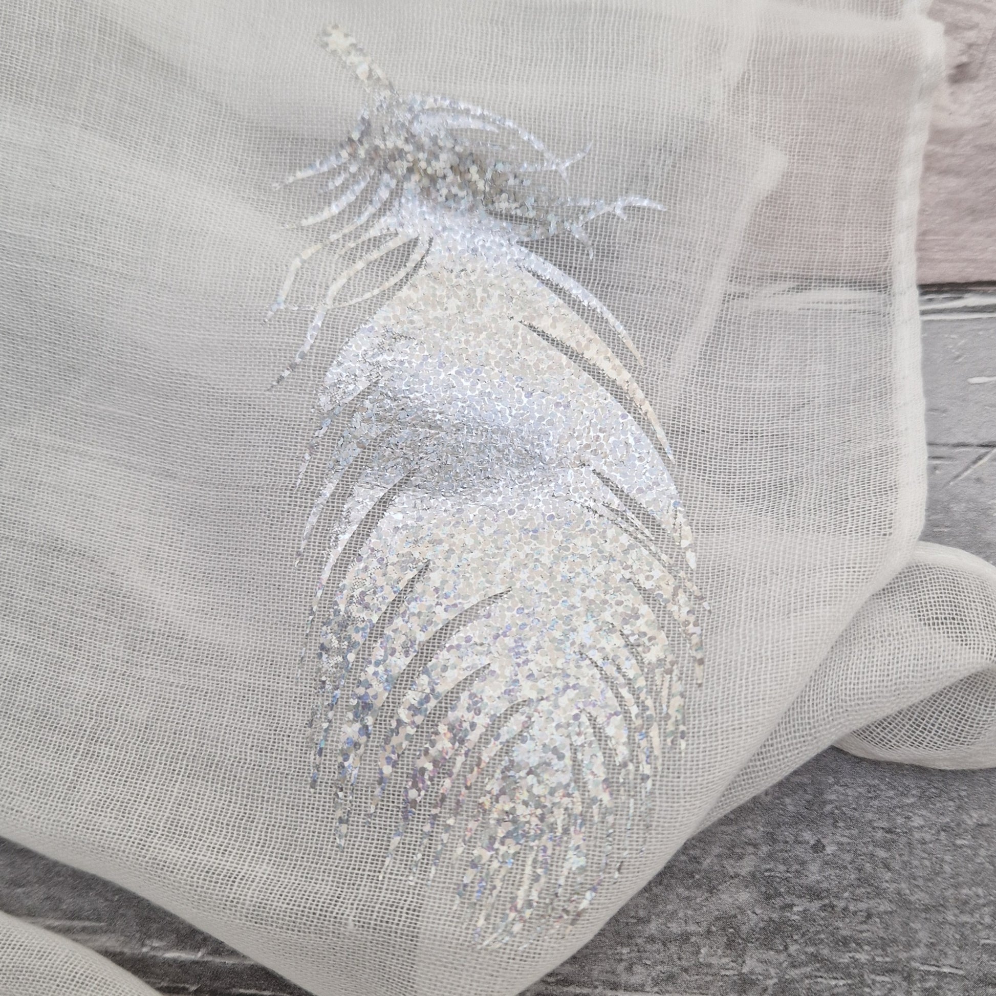 White scarf decorated with holographic silver feather print.