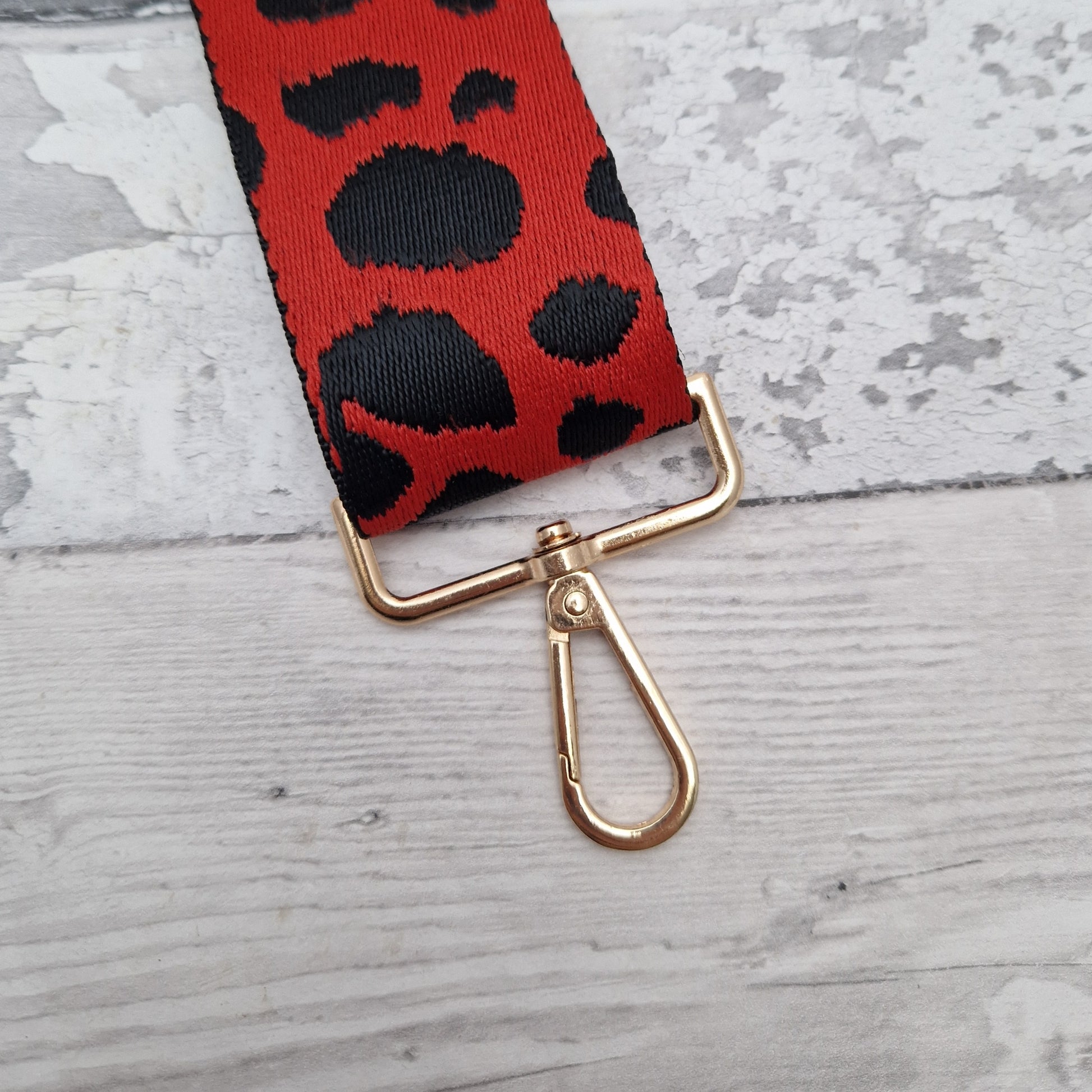 Red Cross body bag strap decorated with irregular black spots.