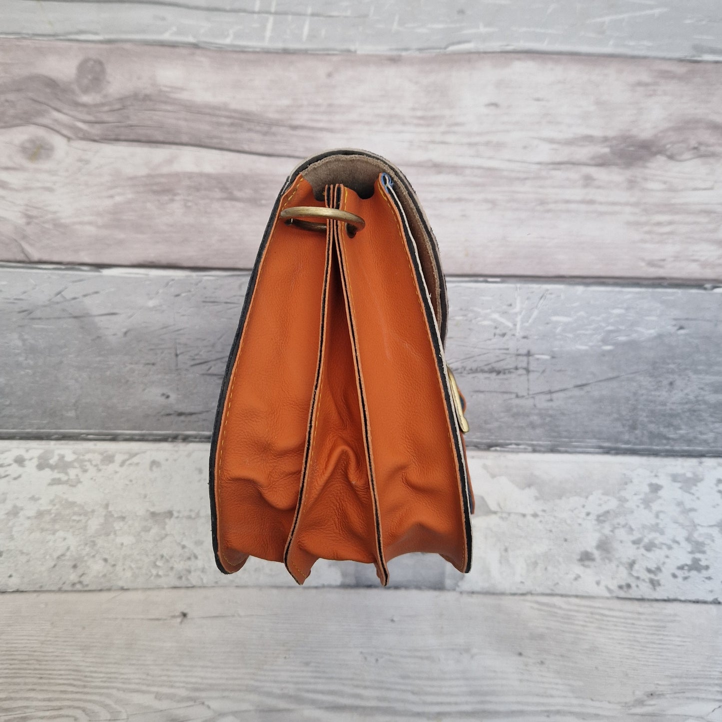 Orange leather handbag with a textured animal print panel.