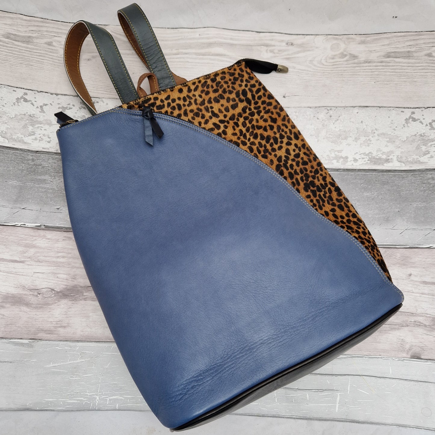 Stone blue coloured leather back pack with a textured panel featuring a Cheetah Print.