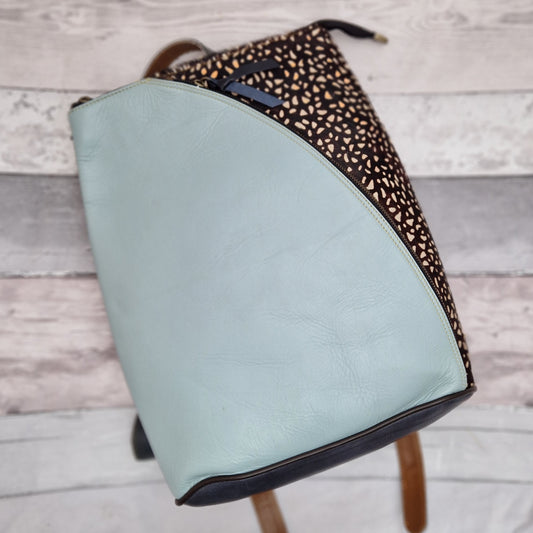 Aquamarine blue leather back pack with a dark printed textured side panel.