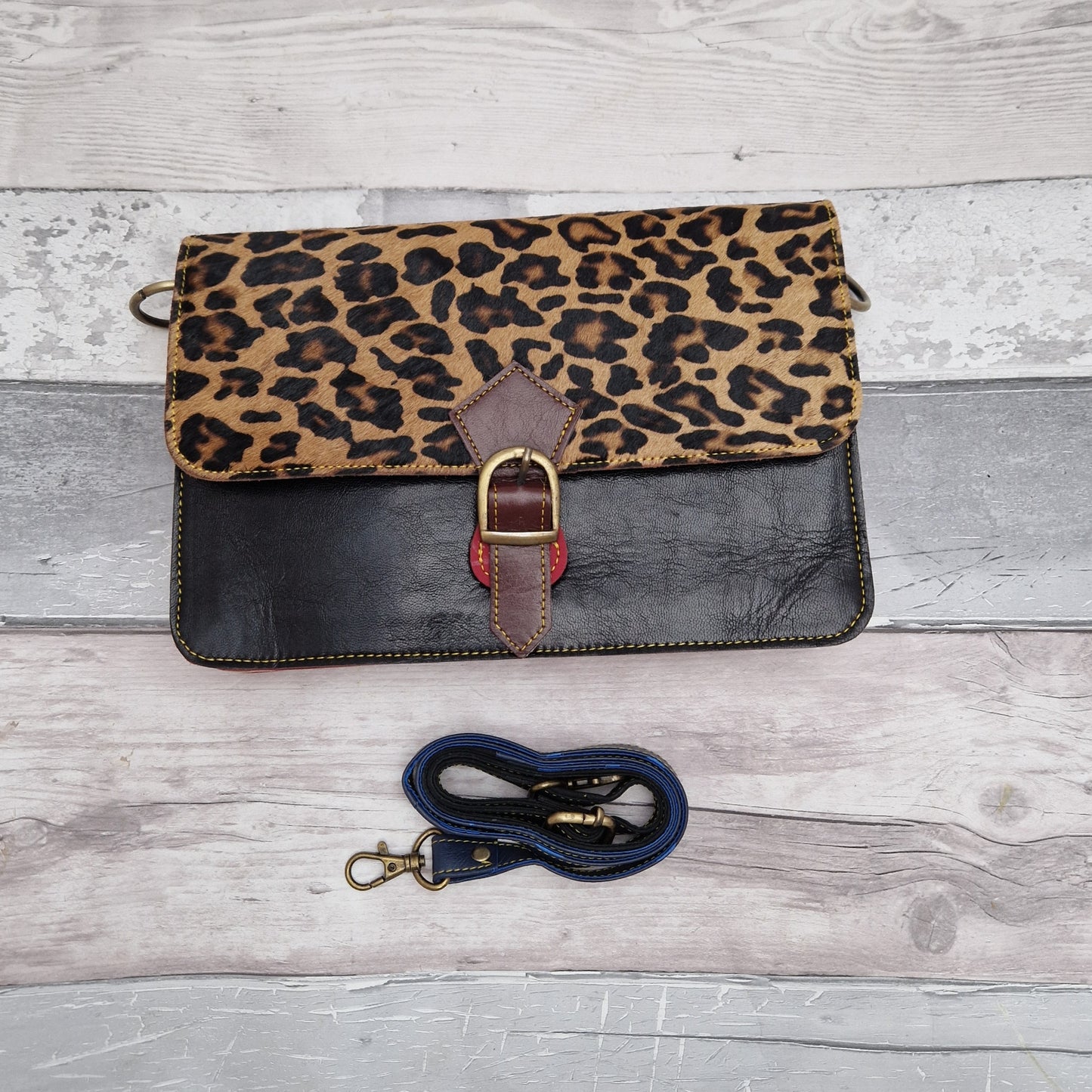 Black leather handbag with a textured leopard print panel.