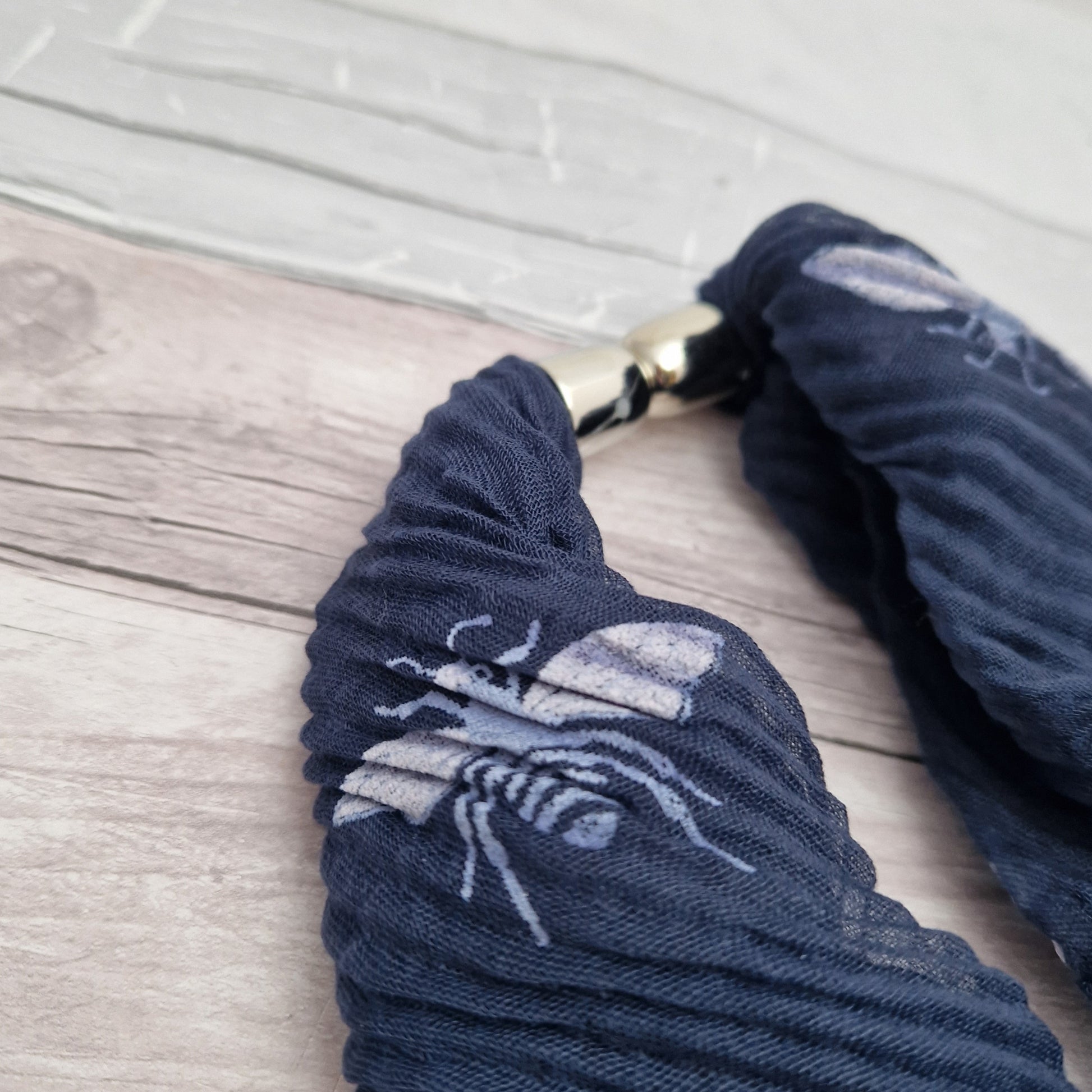 Navy blue neck scarf with magnetic clasp. Decorated with a white bee print.