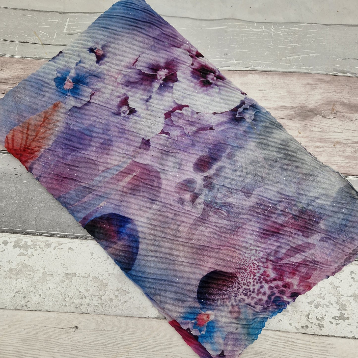 Crinkle scarf decorated with a bouquet of flowers in colours of blue and purple.