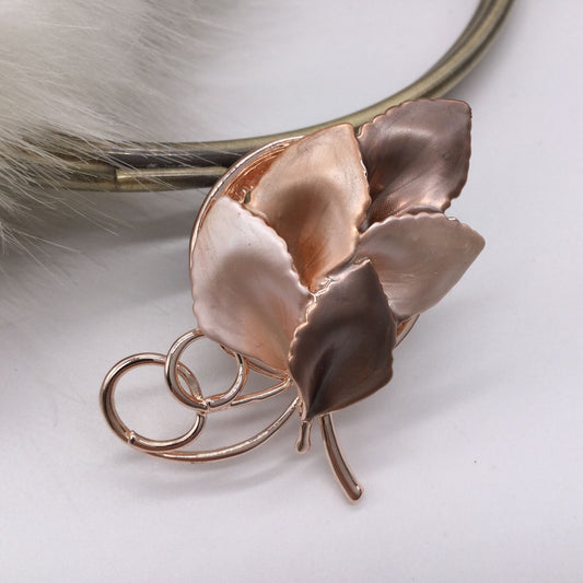 A cluster of leaves in shades of rose gold form a brooch