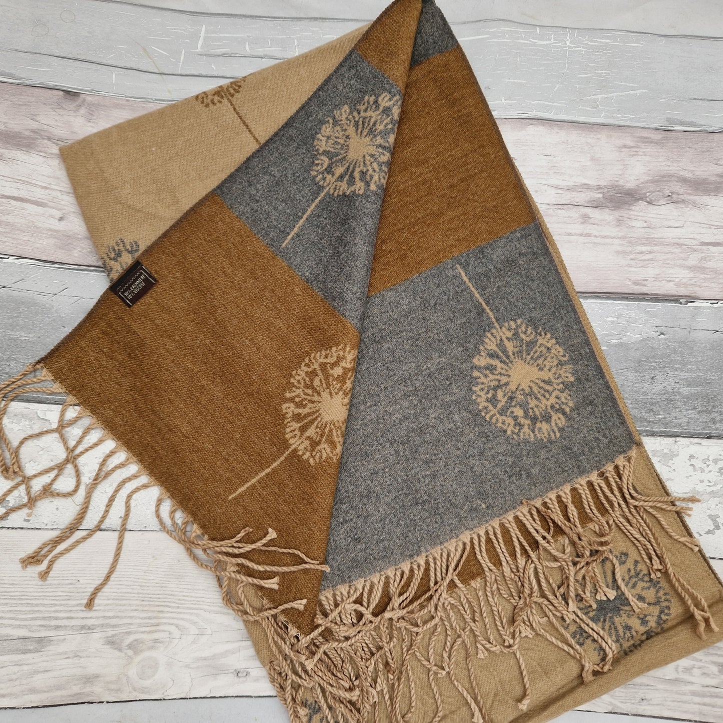 Cashmere blended scarf in a camel colour decorated with dandelion clocks.