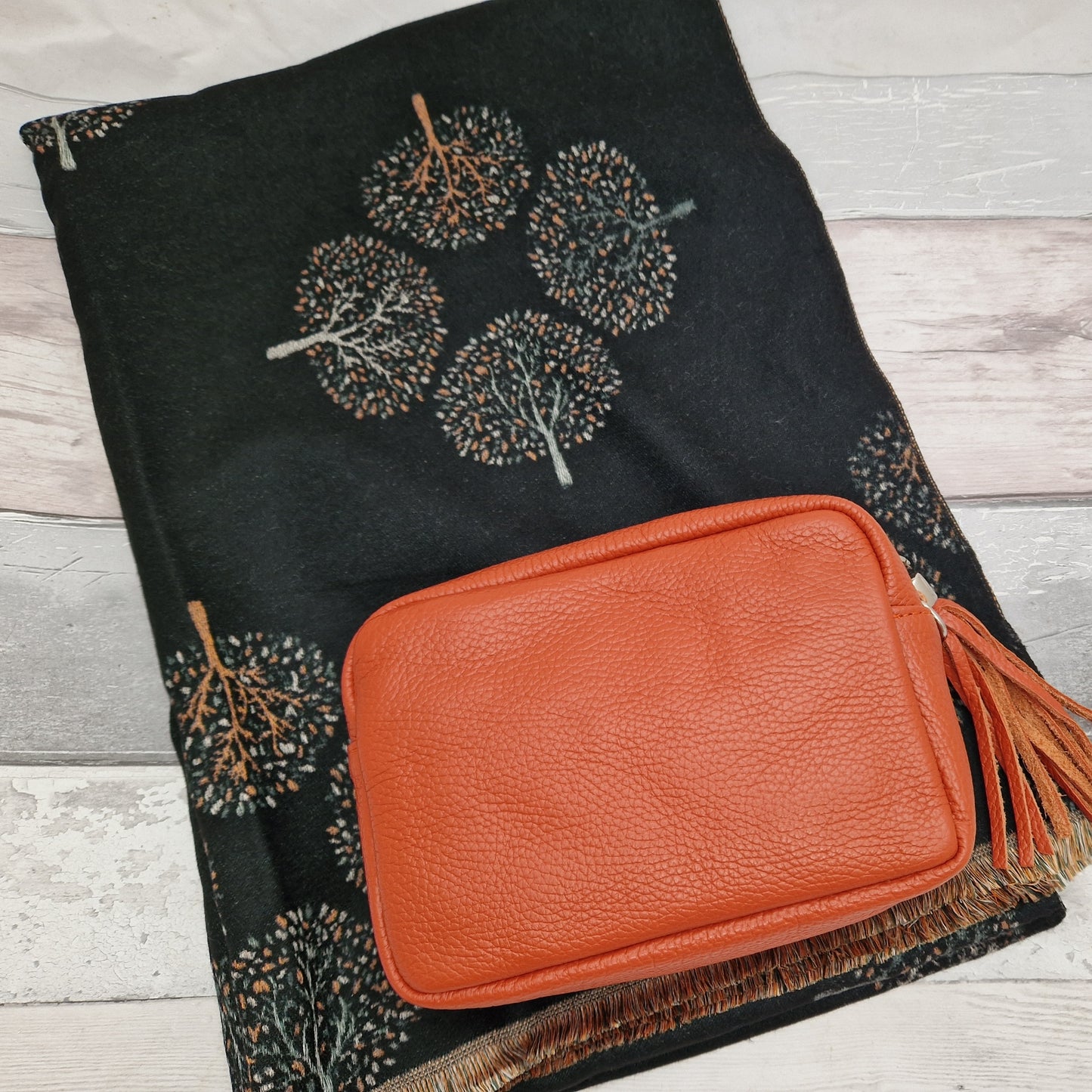 Black scarf with trees of life depicted in warn tones of orange and coffee colours