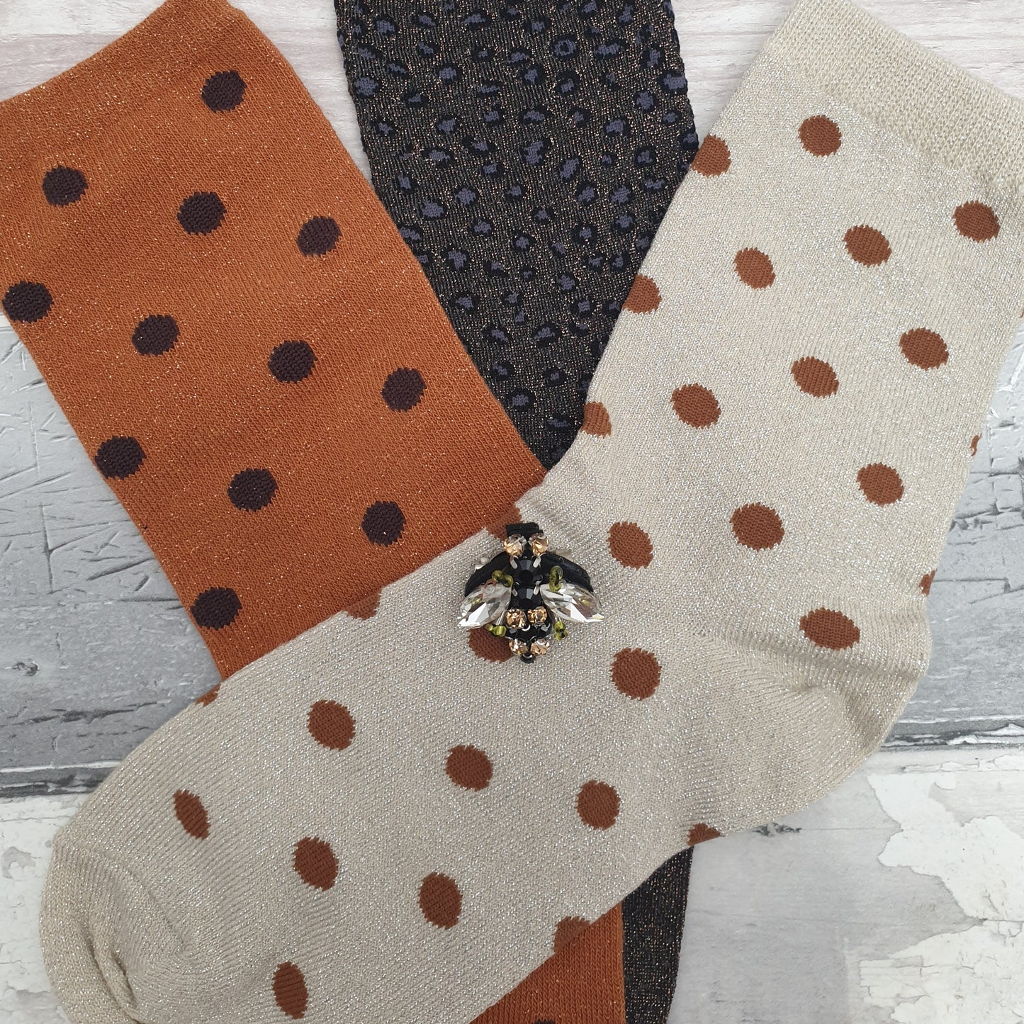 3 Pairs of Socks; cream spotty, copper spotty and silver grey leopard print, all with a sparkly finish. Set is completed with a Bee Brooch.