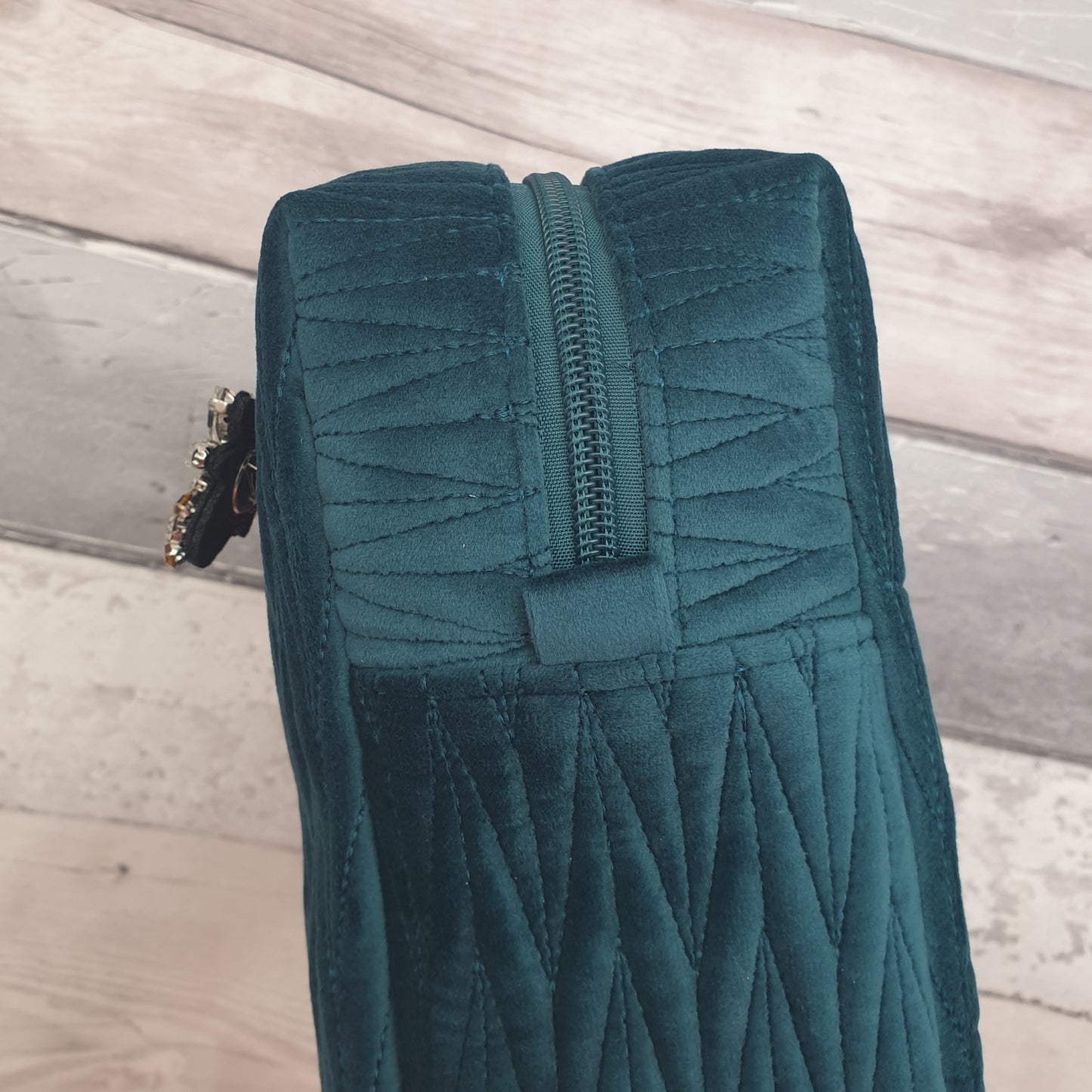 Teal coloured washbag in quilted velvet with a removable Bee Brooch.