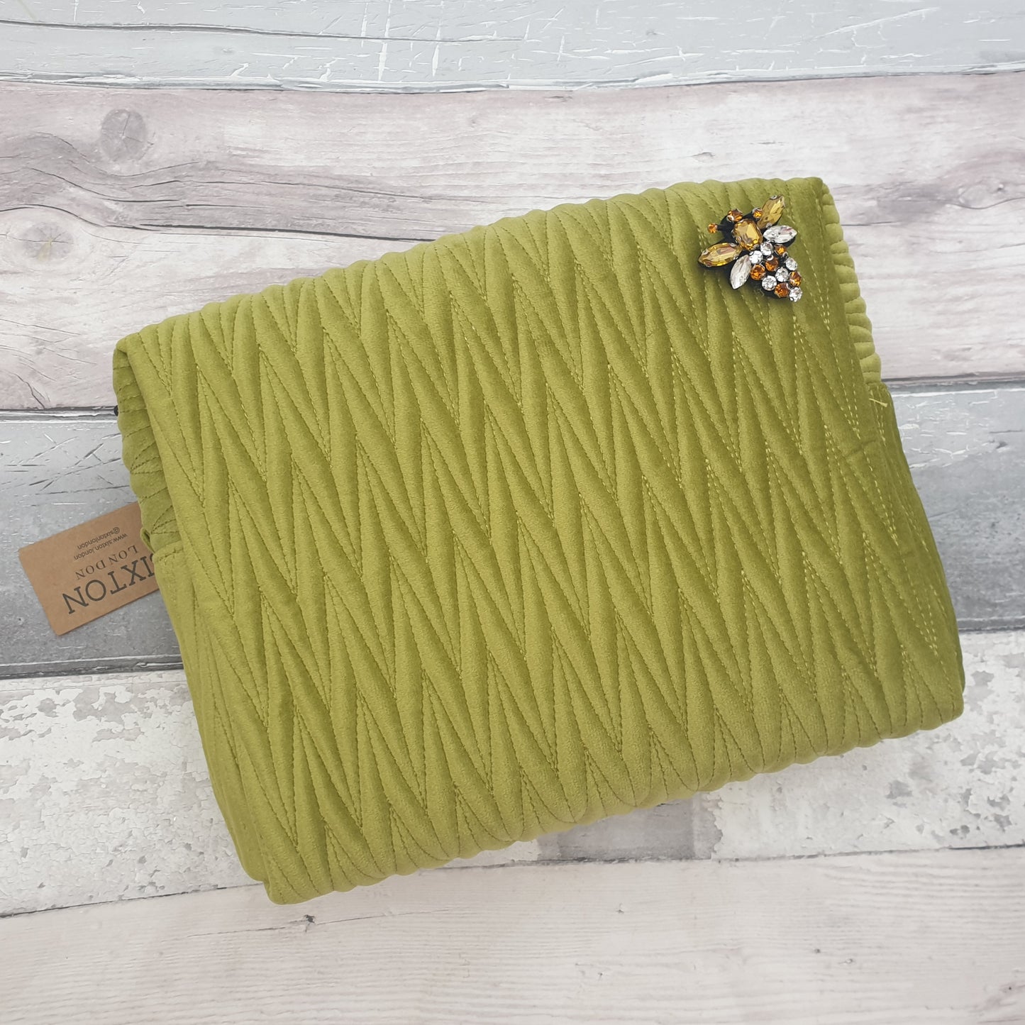 Apple green coloured velvet quilted wash bag with a detachable bee brooch.