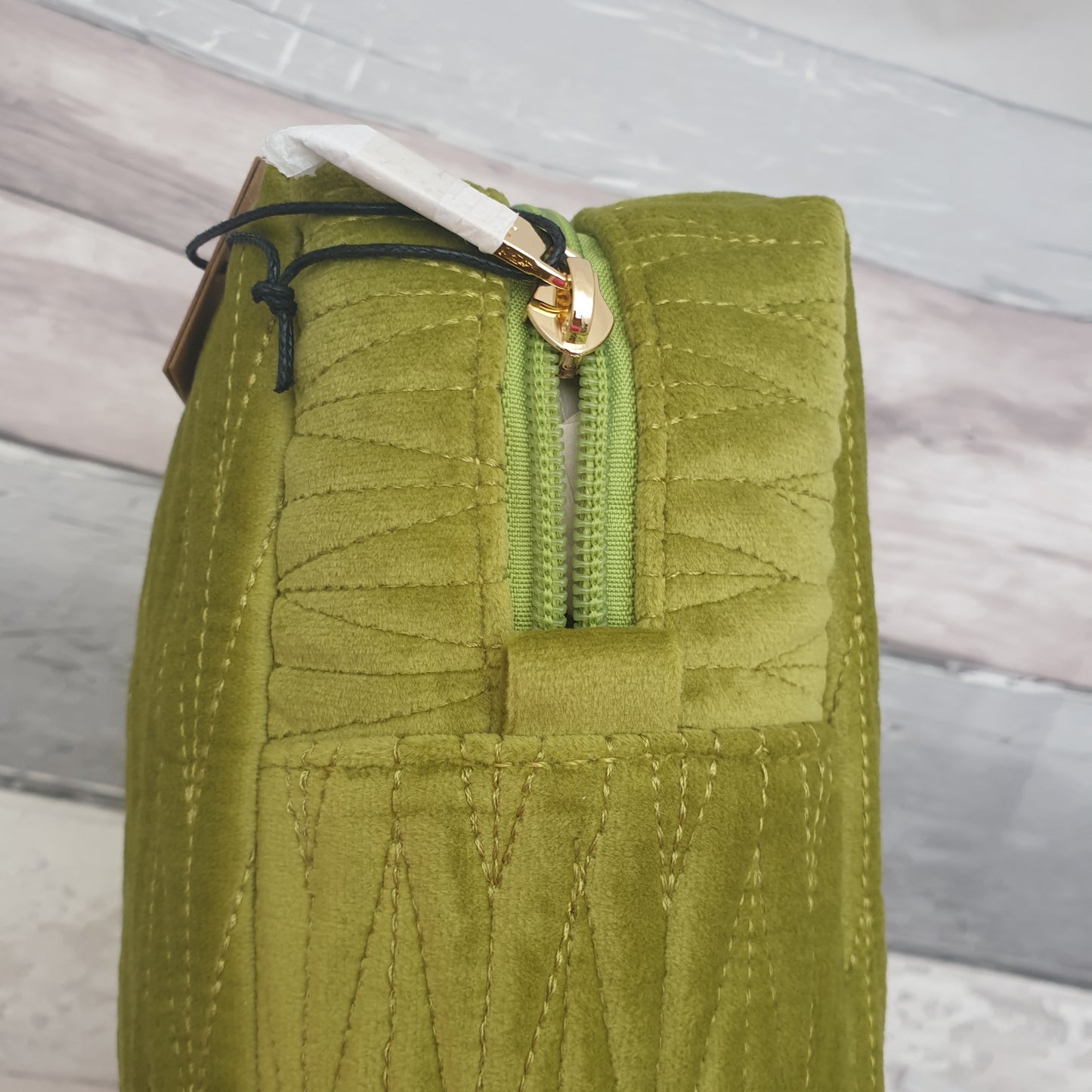 Apple green coloured velvet quilted wash bag with a detachable bee brooch.