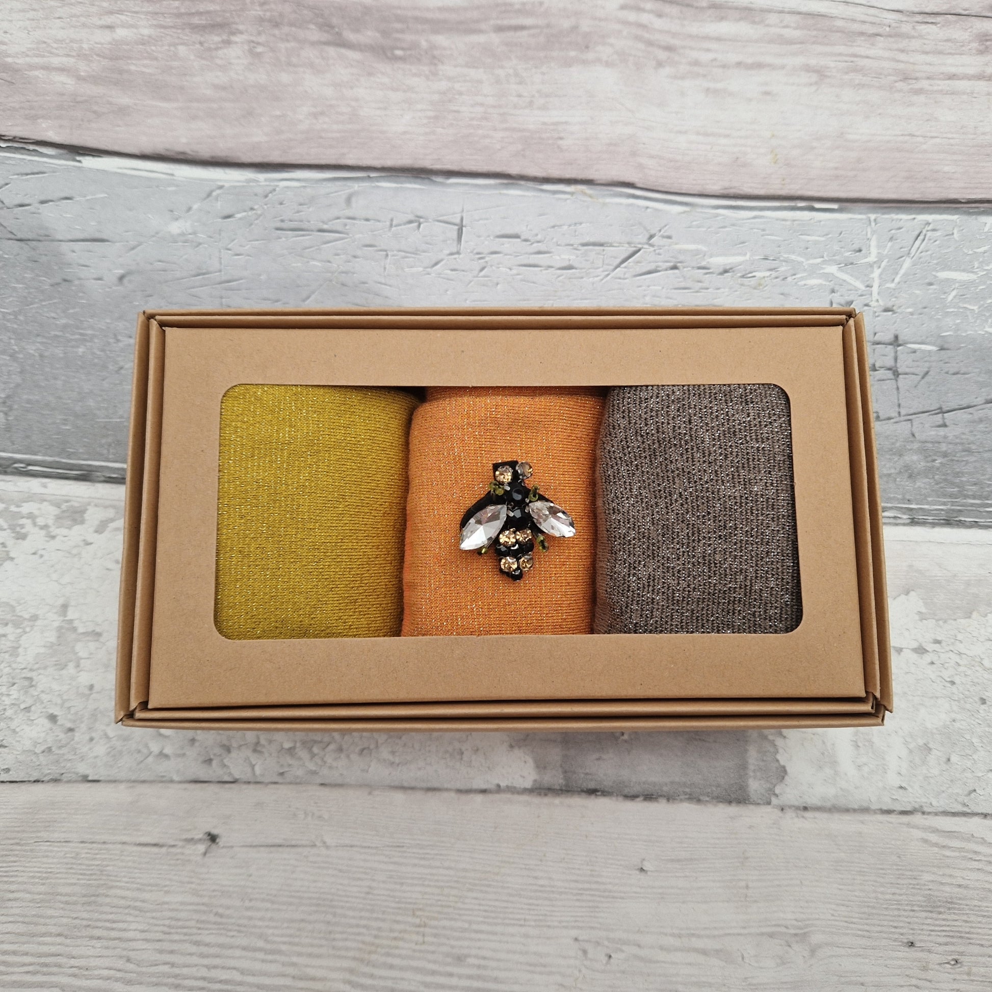 Set of 3 gift boxed sparkly socks in gold, cantaloupe and pewter. Complete with a glass bee brooch.
