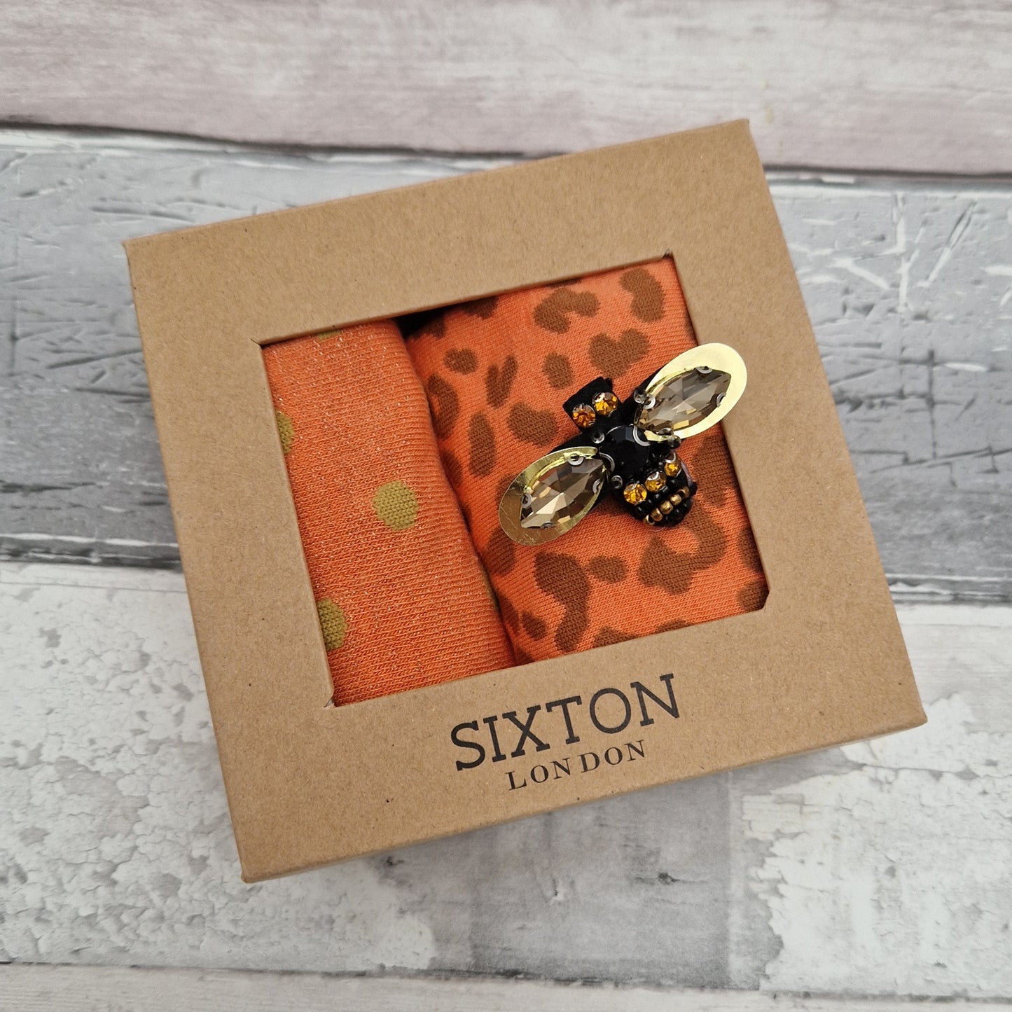 2 Pairs of orange coloured socks presented in a gift box with a sparkling Bee Brooch made of recycled glass.