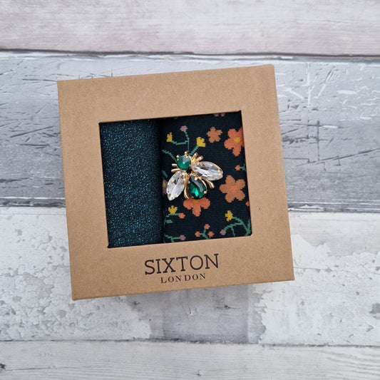 A pair of teal coloured socks in a presentation gift box with a Bee Brooch.