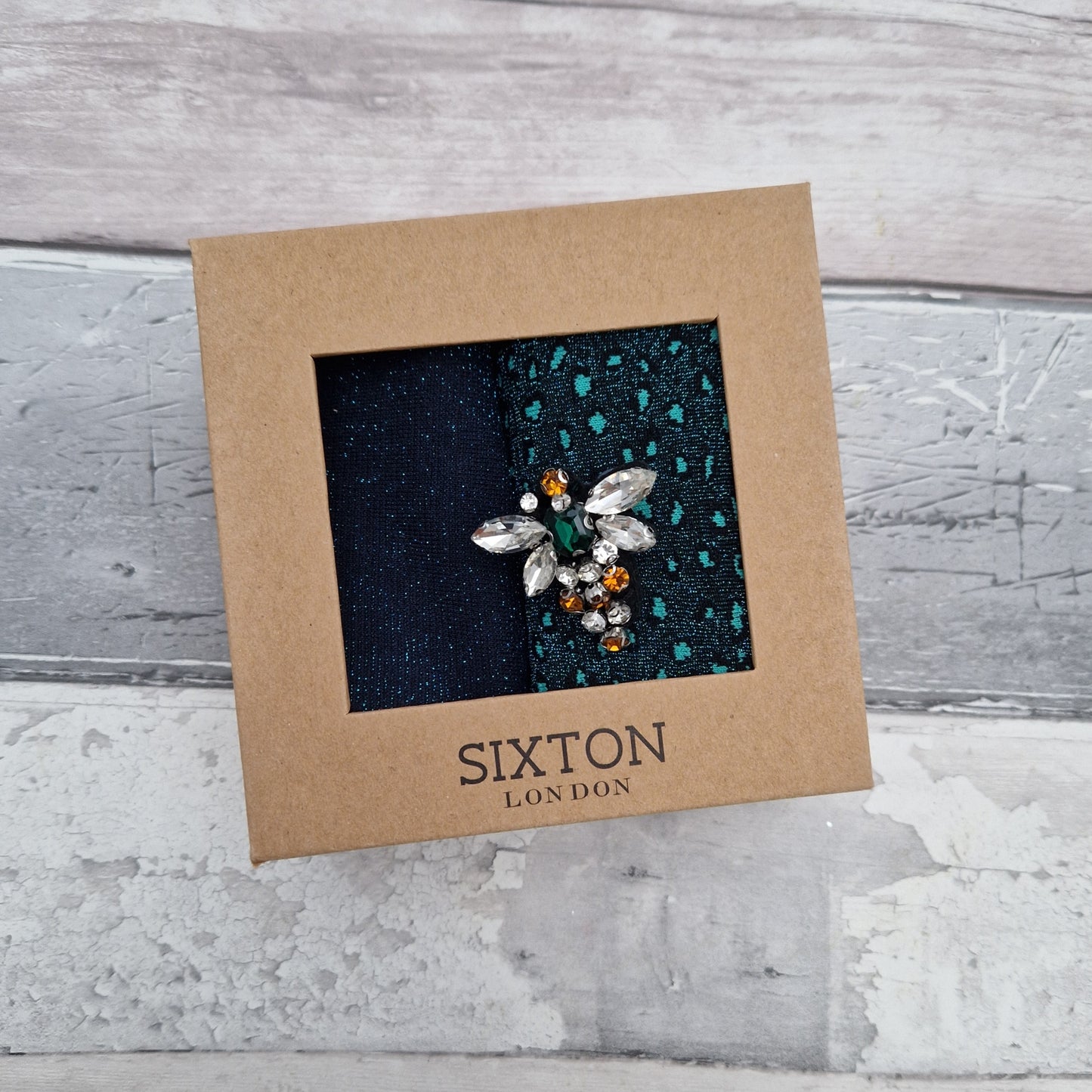 A pair of teal coloured socks in a presentation gift box with a Bee Brooch.