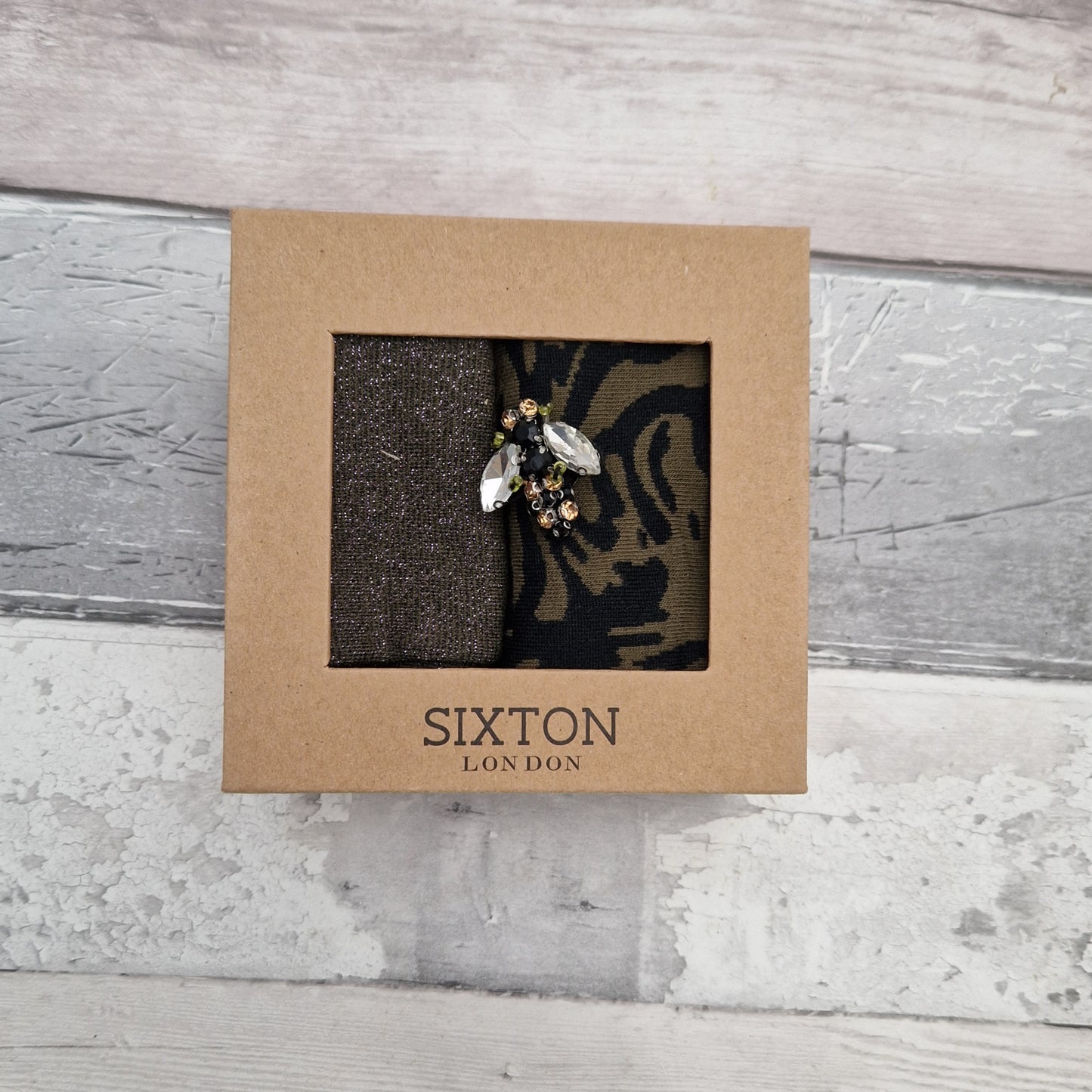 A pair of socks in a presentation gift box with a Bee Brooch.