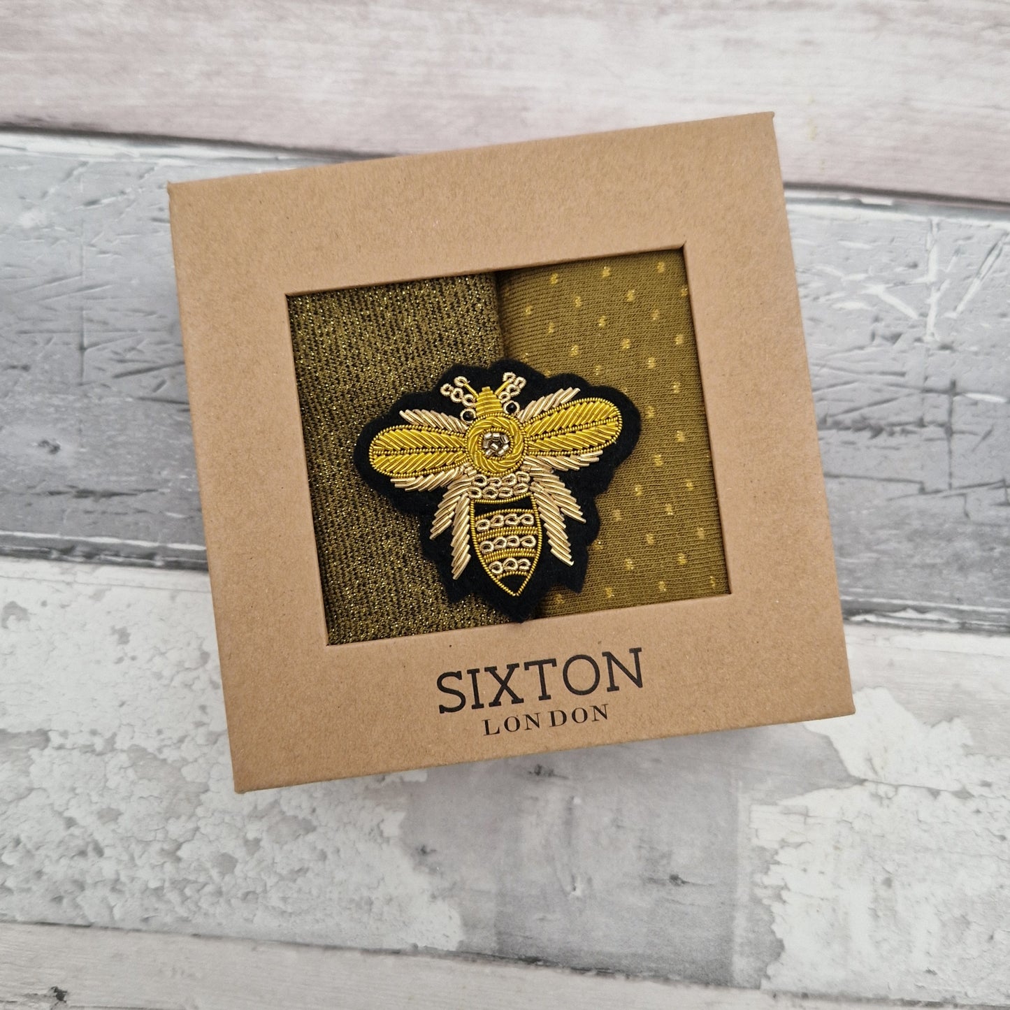 A pair of socks in a presentation gift box with a Bee Brooch.