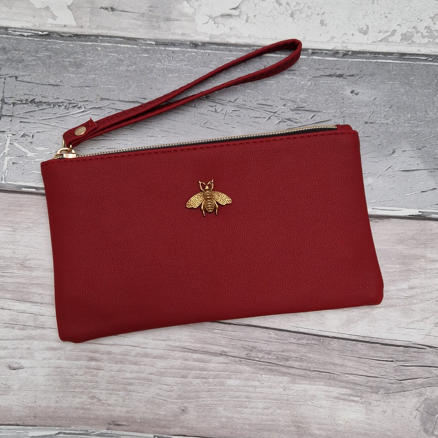 Red Clutch bag with a gold bee emblem.