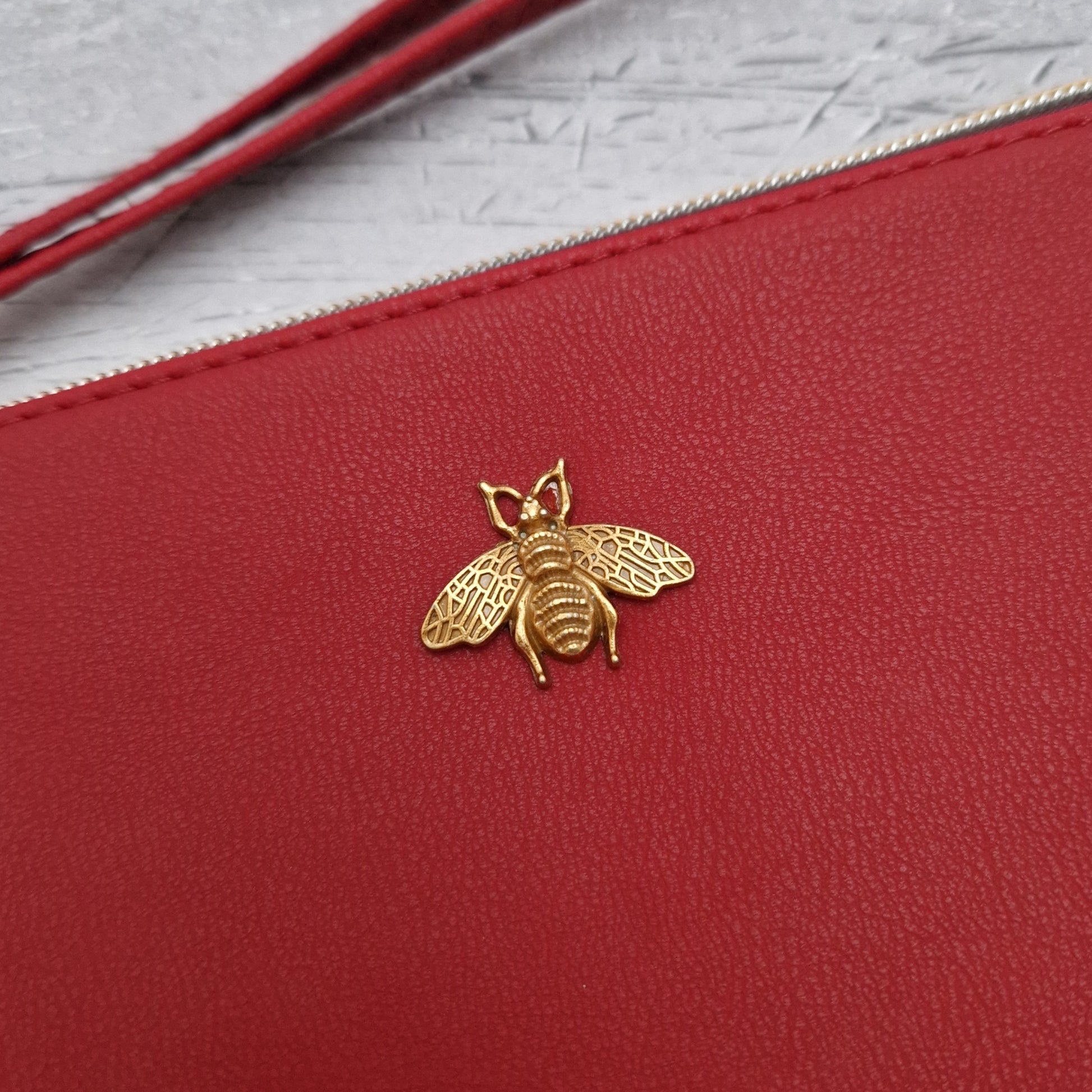 Red Clutch bag with a gold bee emblem.