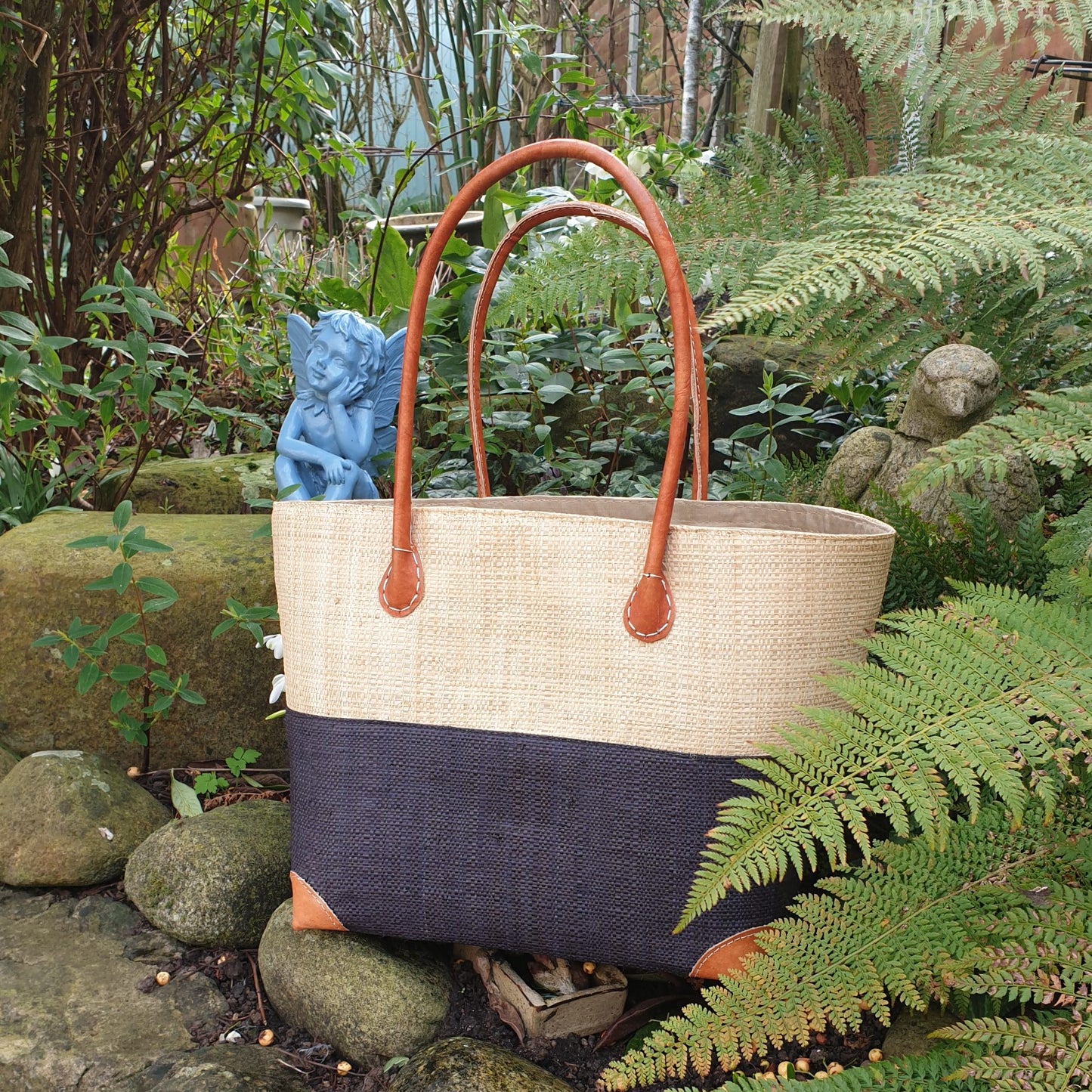 Photo of a medium two tone raffia basket with a natural and black raffia panel and leather handles