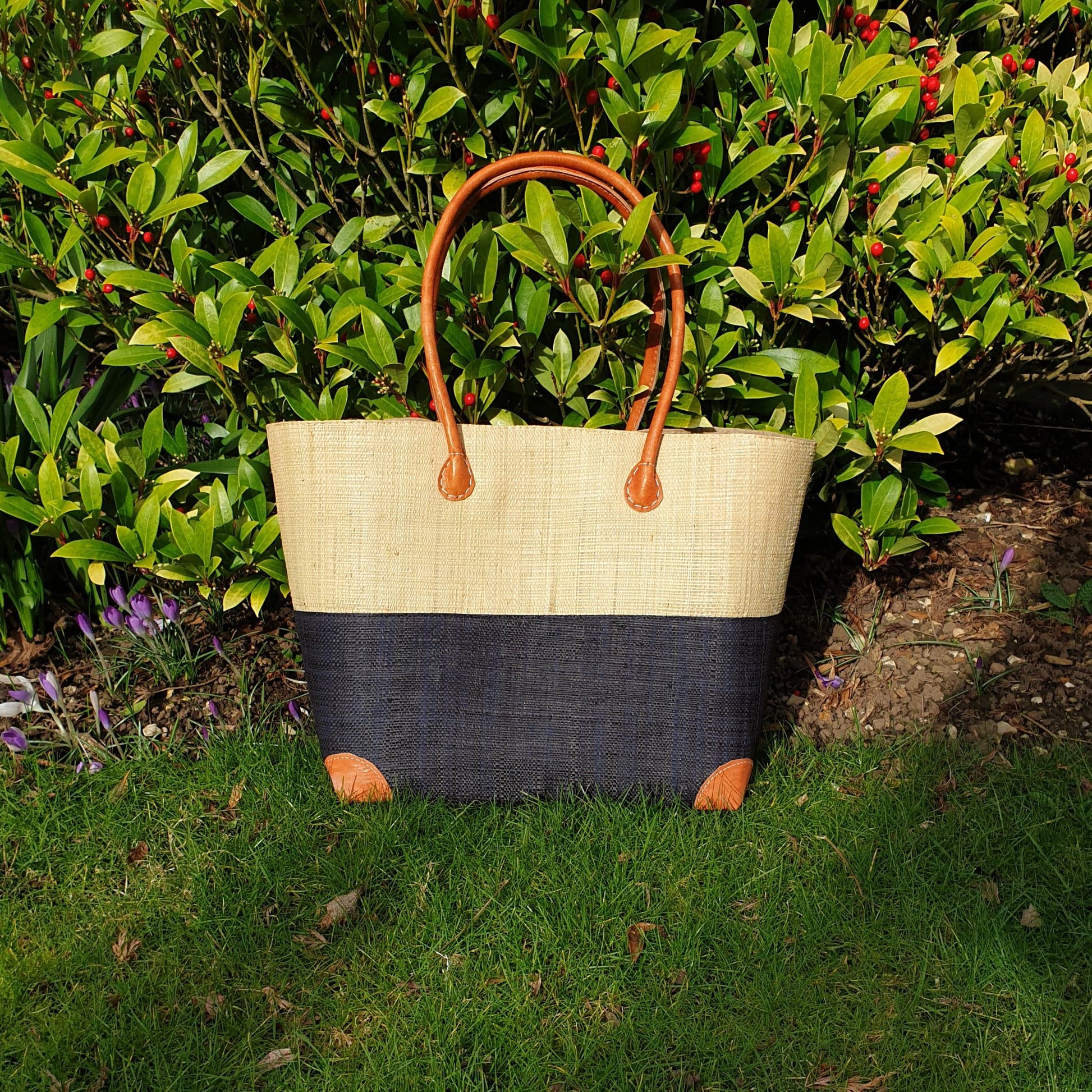 Photo of a small black and natural coloured raffia basket with leather handles