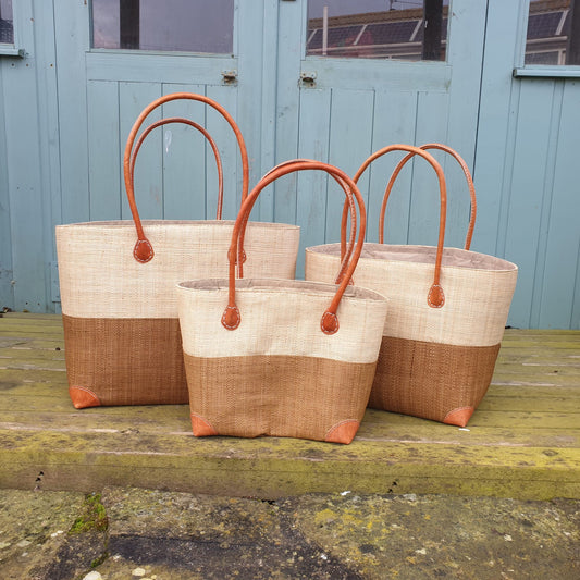 Set of 3, small, medium and large raffia baskets with two tone panels. Natural raffia palm and caramel coloured.
