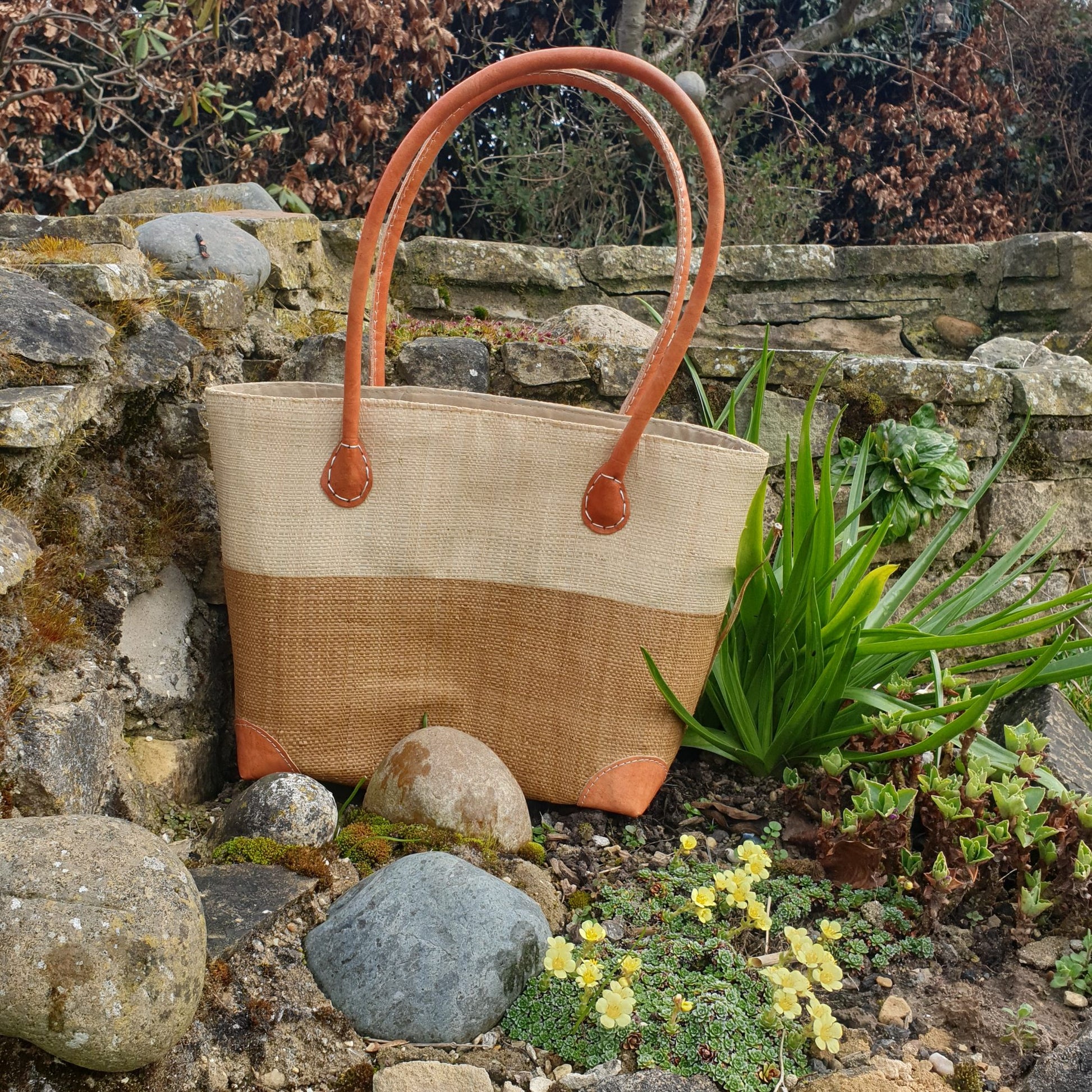 Photo of a small two tone tan and natural raffia basket with leather handles
