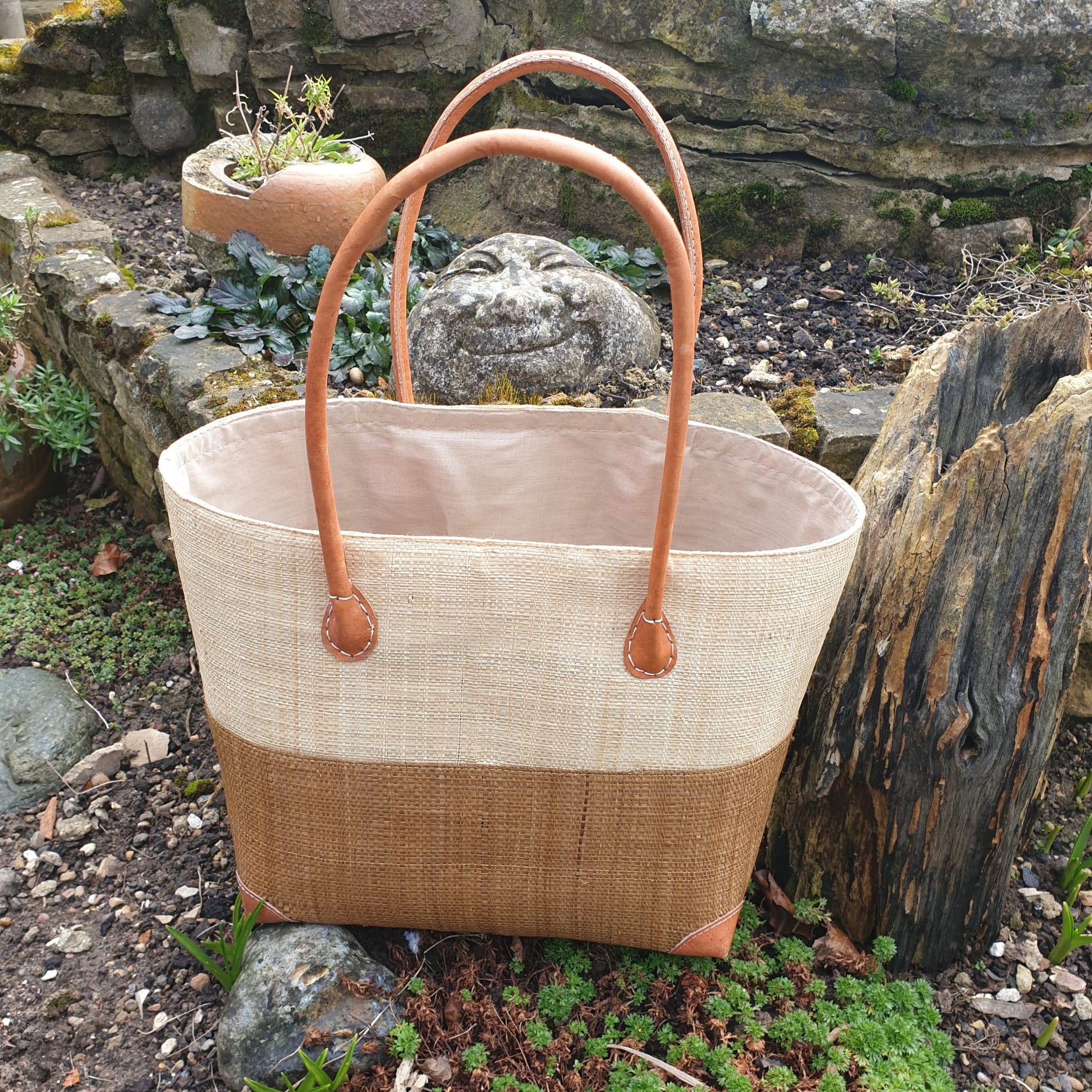 Photo of a medium two tone tan and natural raffia basket with leather handles
